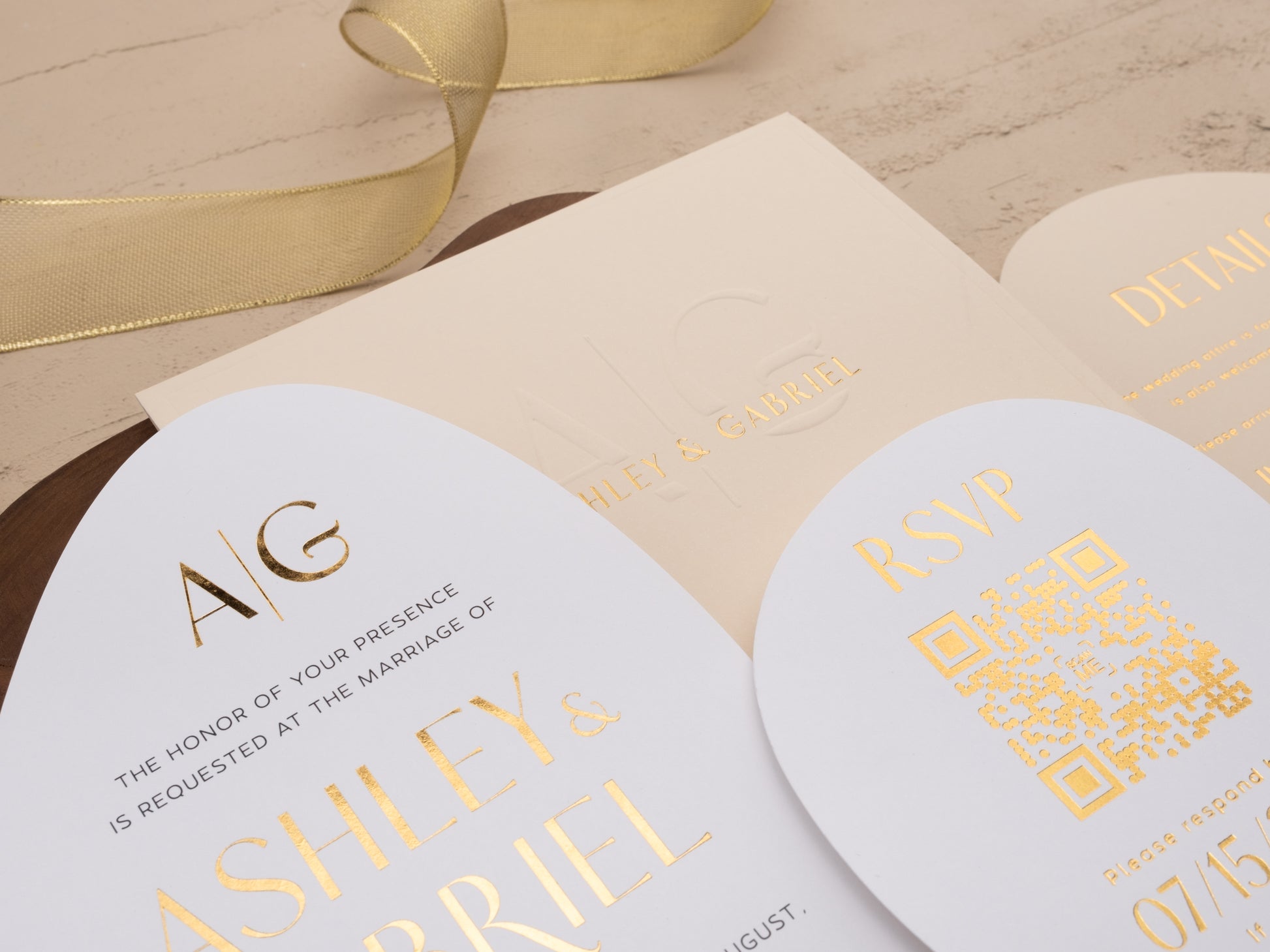 Close-up of ivory wedding invitation suite with gold foil print and embossed envelope