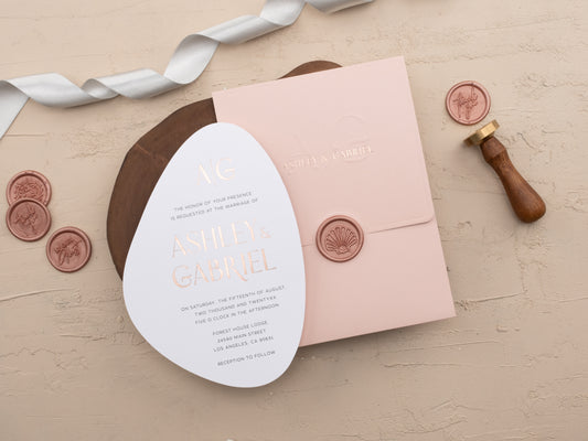 Blush pink envelope with embossed initials and rose gold foil names