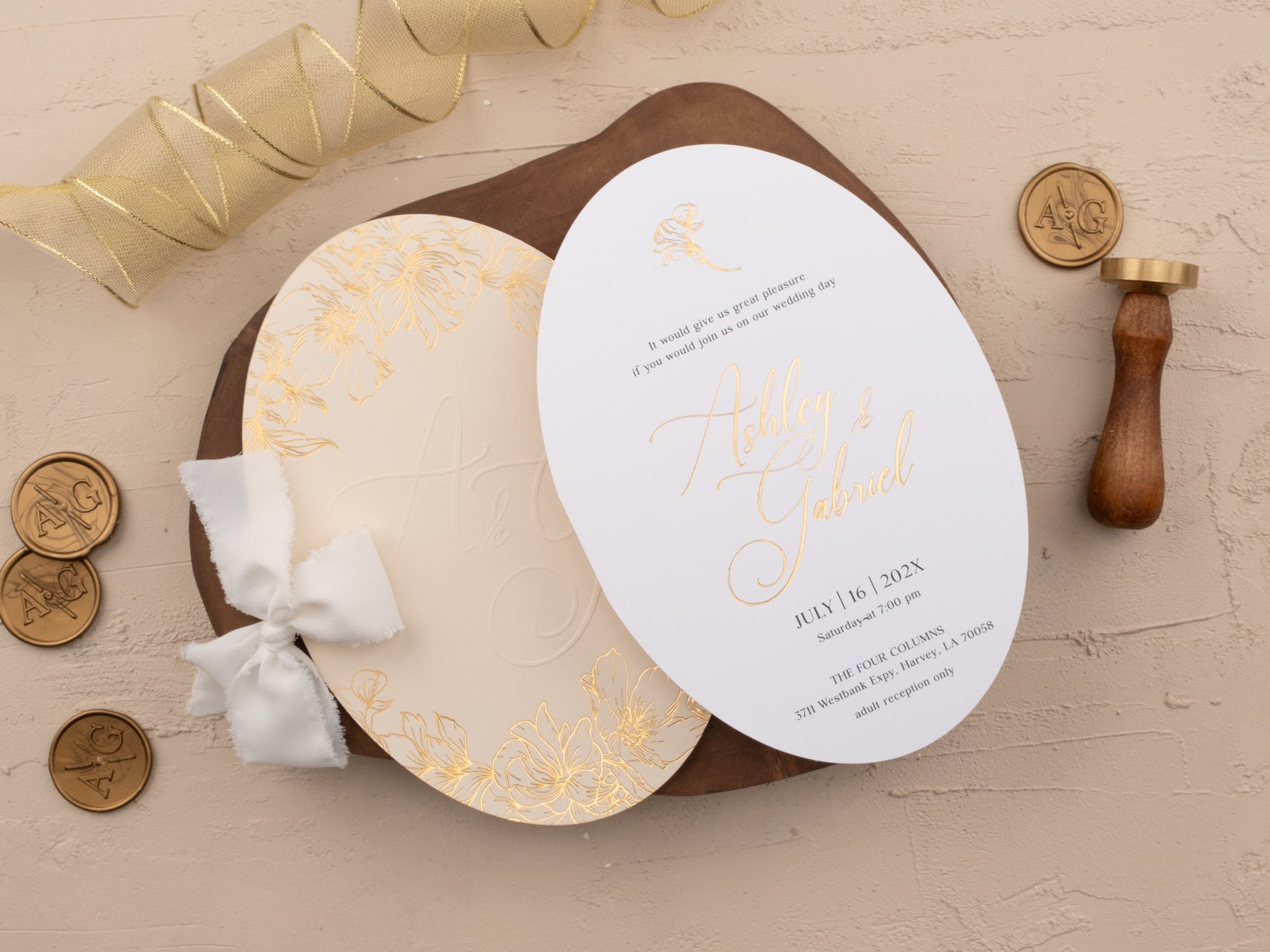 Gold foil wedding invitation with names in script, shown with RSVP and details card