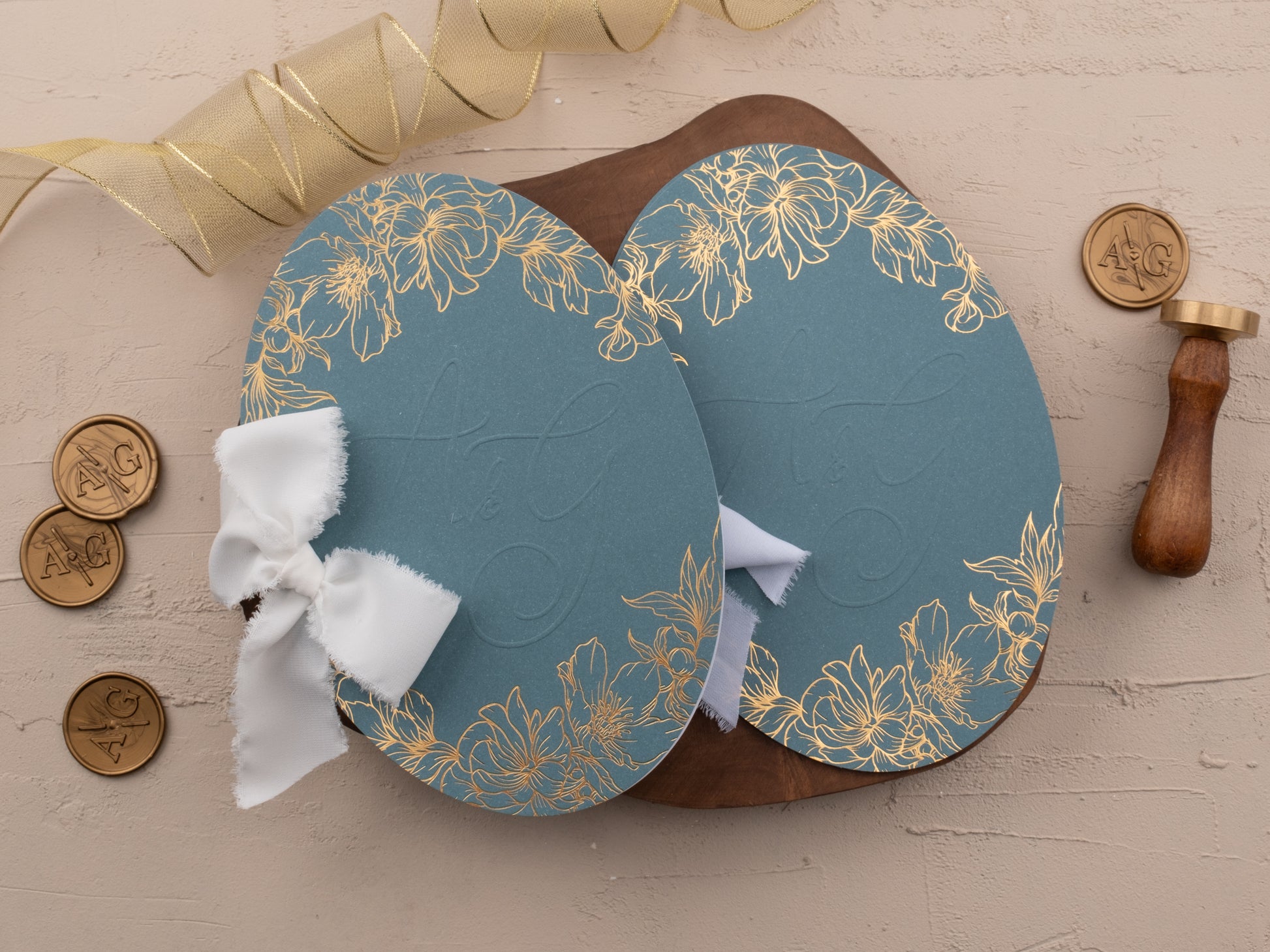 Dusty blue oval wedding invitation suite with gold foil text, shown with matching jacket