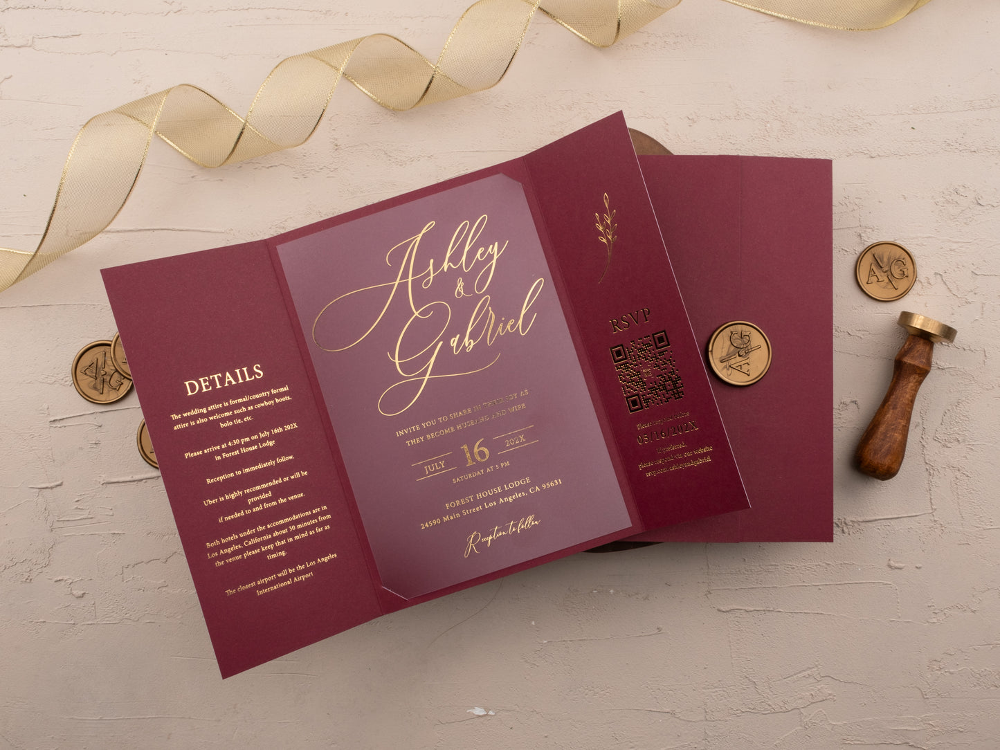 Open burgundy tri-fold wedding invitation with gold foil and RSVP QR code