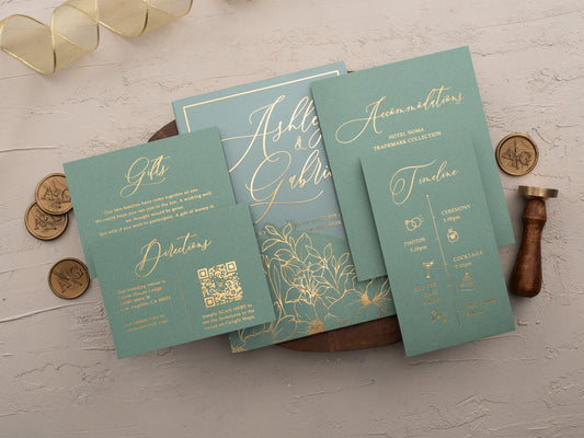 Acrylic wedding invitation with gold foil floral design and matching sage envelope sleeve and Timeline cards