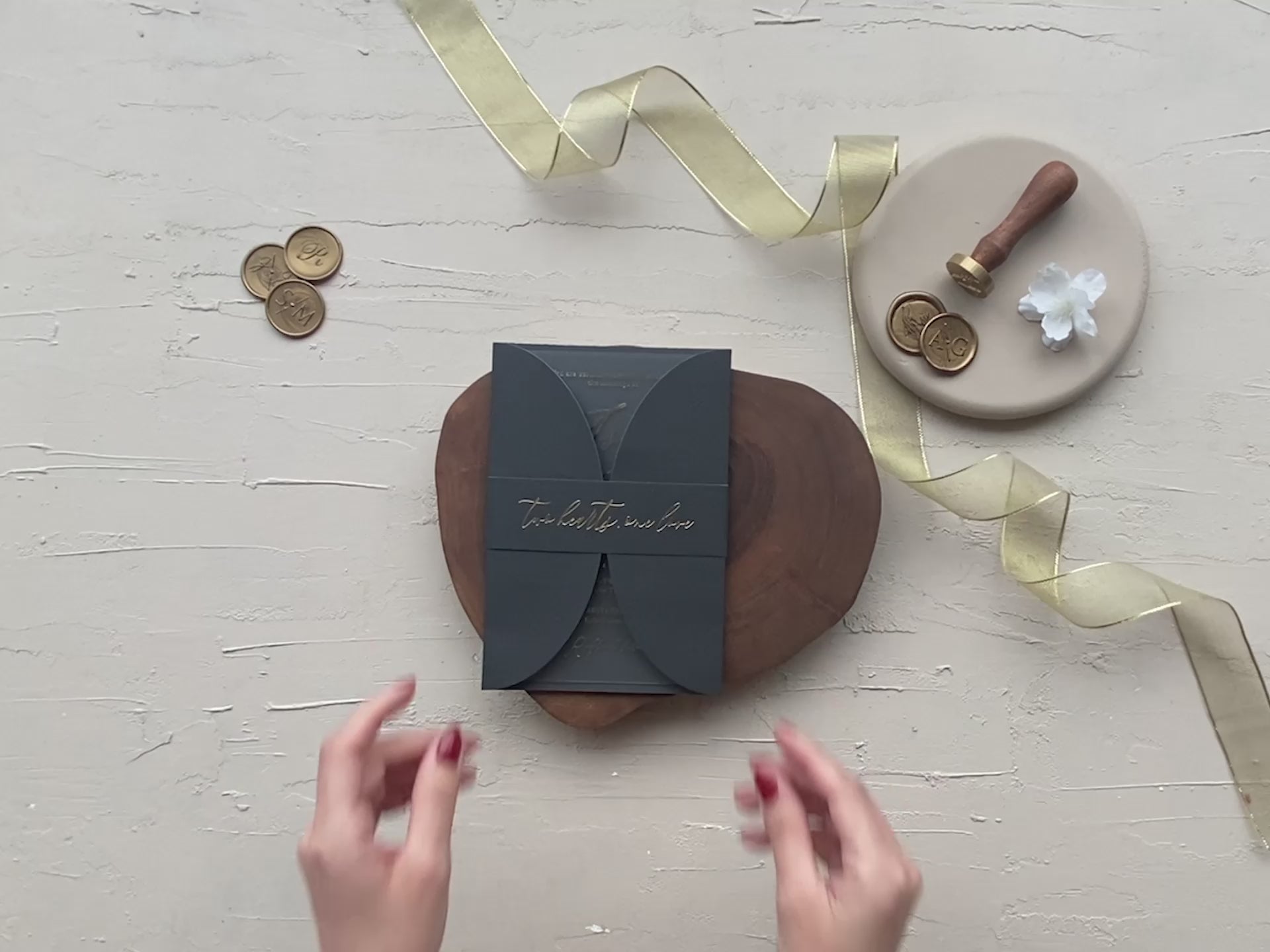 Matte black acrylic wedding invitation suite with gold foil lettering, folded invitation design, luxury RSVP and detail inserts, displayed with wax seals and ribbon.