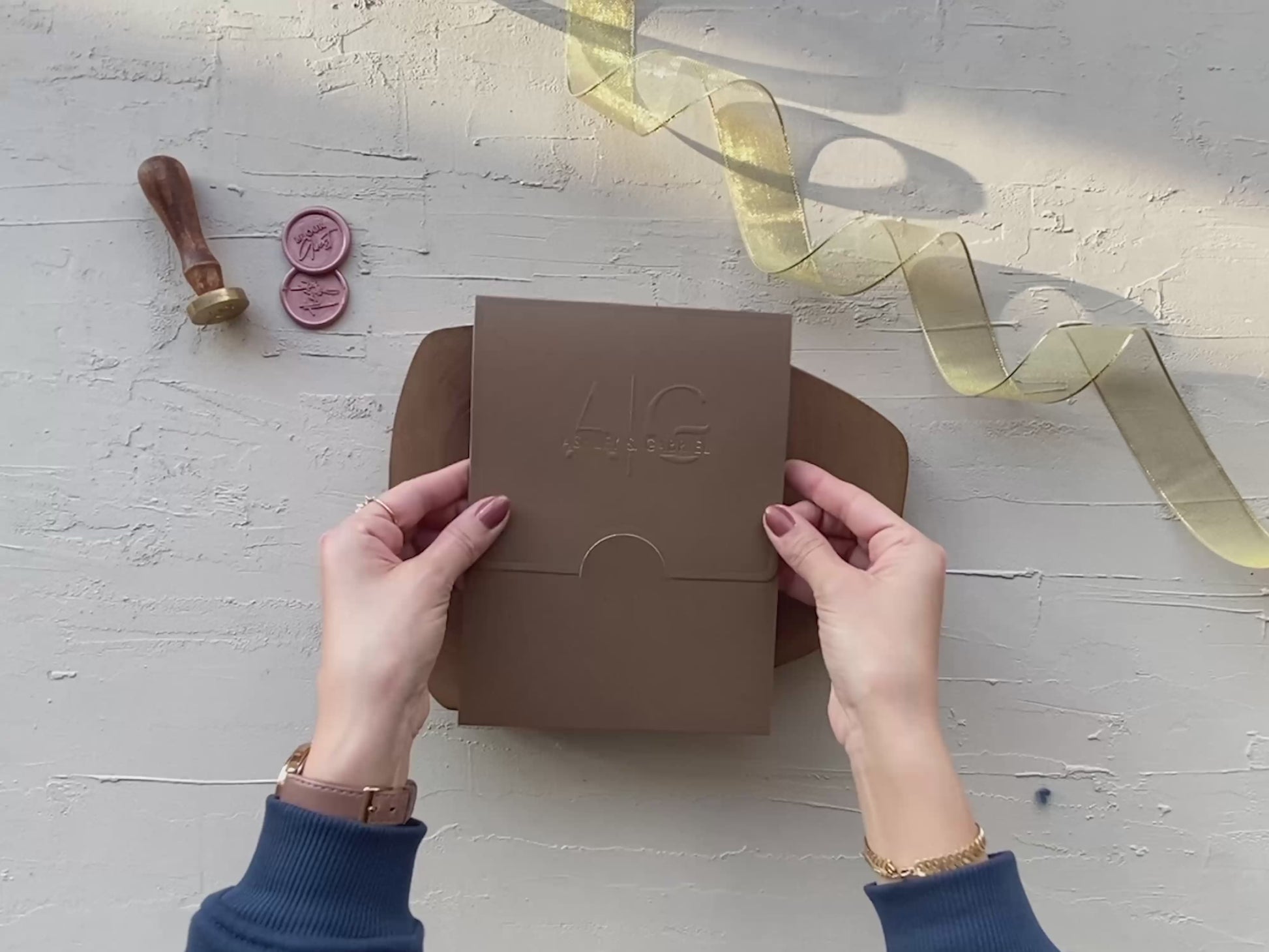Oval wedding invitation with gold print, styled with wax seal and brown envelope